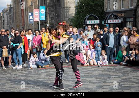 Royal Mile, Édimbourg, Écosse, Royaume-Uni. 27 août 2023. Bien que le Fringe Festival d'Édimbourg se termine le lundi 28 août, il n'y avait pas de sécurité ou de personnel Fringe autour de la High Street pour surveiller les foules et le temps des spectacles d'artistes de rue. Cependant, il y avait encore un large public congressant pour se divertir. Sur la photo : Witty Looks Cheeky et Daiki du Japon divertissent la foule avec leur numéro de comédie sur le terrain de High Street inférieur. Crédit : Arch White/alamy Live News. Banque D'Images