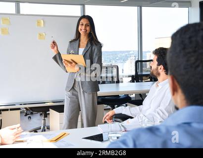 Heureuse femme d'affaires indienne professionnelle donnant la présentation dans le bureau. Banque D'Images