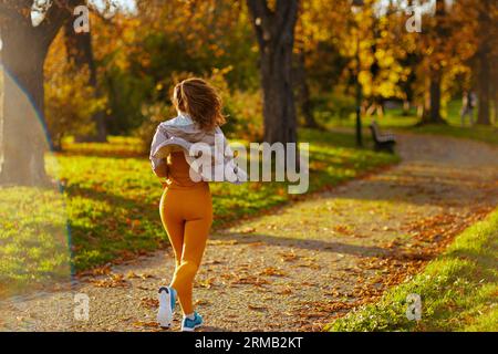 Bonjour automne. Vu de derrière femme dans des vêtements de fitness dans le parc en cours d'exécution. Banque D'Images