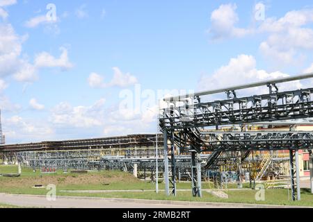 Un grand chevalet de tuyauterie en fer métallique avec tuyaux, fils électriques et équipement à la raffinerie industrielle de la raffinerie pétrochimique. Banque D'Images