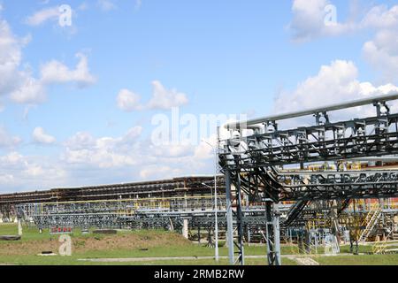 Un grand chevalet de tuyauterie en fer métallique avec tuyaux, fils électriques et équipement à la raffinerie industrielle de la raffinerie pétrochimique. Banque D'Images