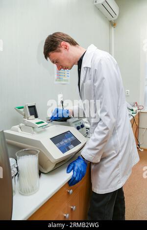 Scientifique avec la main gantée plaçant l'échantillon d'ADN dans PCR-cycler en temps réel. Banque D'Images