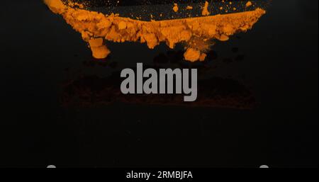 Curcuma, curcuma longa, poudre tombant sur fond noir, épices indiennes Banque D'Images