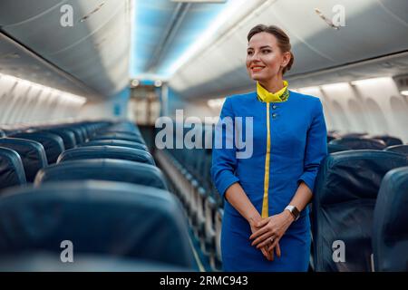 Un employé de bord joyeux debout dans la cabine passager de l'avion Banque D'Images