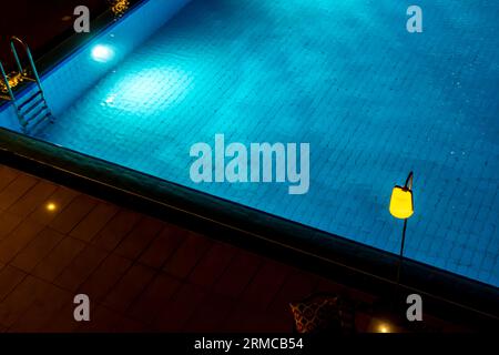 Lampadaire jaune au-dessus de l'eau bleue de la piscine, prise de vue de nuit. Banque D'Images
