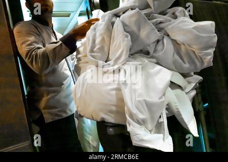 Personnel de ménage avec chariot avec draps usagés, linge usagé à côté de la chambre de l'hôtel. Employé de ménage de l'hôtellerie de nettoyage Banque D'Images