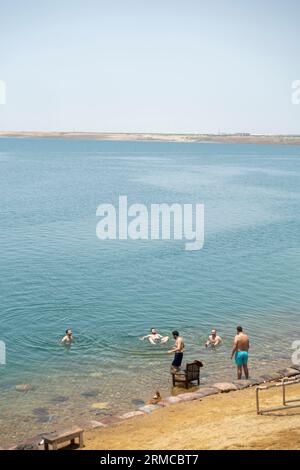 Touristes sur la côte de la mer Morte dans la zone de baignade restreinte, les gens couverts de boue prêts à nager dans la mer Morte, Jordanie Banque D'Images