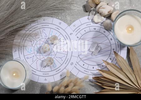 Roue du zodiaque, thème natal, bougie allumée, dés d'astrologie et pierres sur table grise, pose plate Banque D'Images