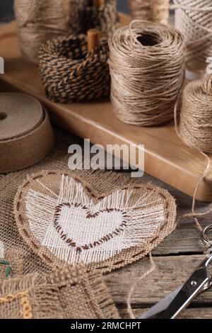 Coeur de toile de jute avec des points et des bobines de ficelle sur table en bois Banque D'Images