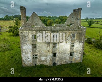 Vue aérienne du château médiéval de Glinsk maison-tour fortifiée en Irlande avec structure symétrique cinq longues cheminées hautes de chaque côté, County Calway Banque D'Images