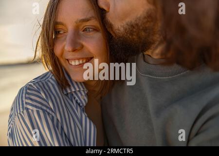 Gros plan de couple amoureux embrassant et embrassant tout en marchant le long de la plage par jour ensoleillé venteux Banque D'Images