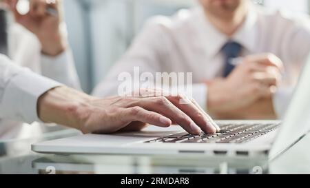 Vue en gros plan de deux jeunes collègues travaillant sur un ordinateur portable au bureau Banque D'Images