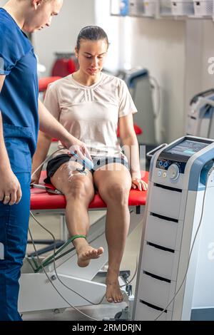 Médecin utilisant une machine pour traiter les articulations du genou d'un patient. Banque D'Images