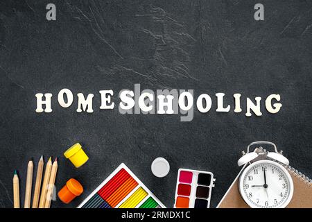 Mot homeschooling fait de lettres en bois sur un fond noir, vue de dessus. Banque D'Images