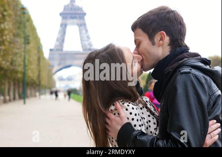 Jeune couple romantique s'embrassant près de la Tour Eiffel à Paris Banque D'Images