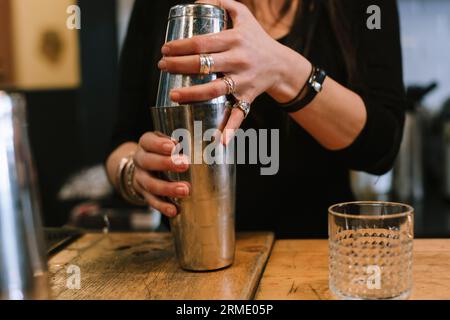 La jeune barwoman prépare un cocktail alcoolisé au bar. Banque D'Images