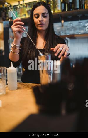 La jeune barwoman prépare un cocktail alcoolisé au bar Banque D'Images