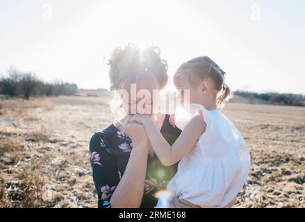 mère tenant sa fille et lui embrassant la main Banque D'Images