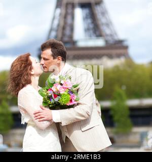 Juste un couple marié s'embrasse près de la Tour Eiffel Banque D'Images