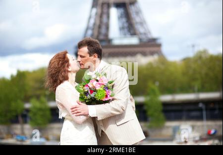 Juste un couple marié s'embrasse près de la Tour Eiffel Banque D'Images
