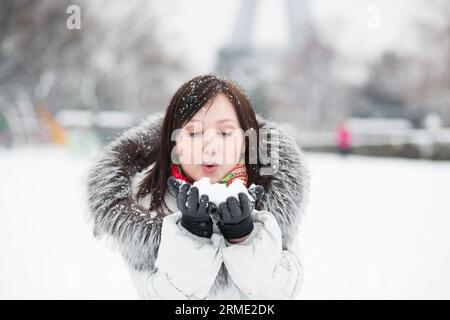 Belle jeune fille soufflant sur la neige Banque D'Images