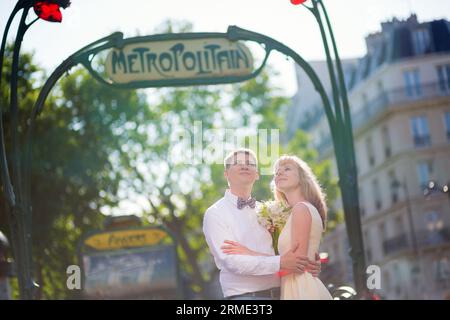 Juste un couple marié avec un panneau de métro parisien Banque D'Images