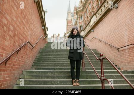 Femme riant dans les escaliers à la gare King's Cross à Londres, Royaume-Uni. Banque D'Images