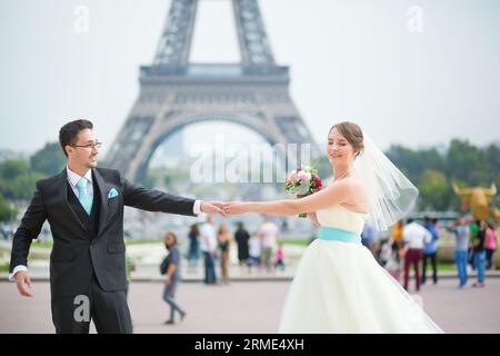 Heureux couple juste marié dansant près de la tour Eiffel à Paris Banque D'Images
