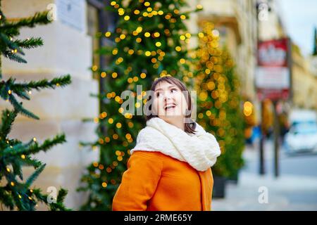 Heureux jeune touriste à Paris un jour d'hiver, décoré arbre de Noël avec des lumières dorées en arrière-plan Banque D'Images