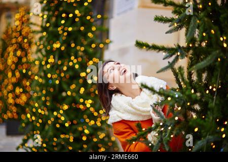 Heureux jeune touriste à Paris un jour d'hiver, décoré arbre de Noël avec des lumières dorées en arrière-plan Banque D'Images