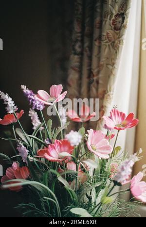 Fleurs artificielles dans un vase près d'une fenêtre, décoration intérieure Banque D'Images