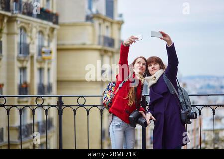 Deux belles filles joyeuses à Paris prenant selfie en utilisant un téléphone portable sur Montmartre Banque D'Images