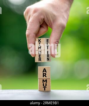 Des piles verticales de cubes en bois forment les expressions allemandes 'Kinderarmut' (pauvreté des enfants) et 'Elternarmut' (pauvreté des parents). Banque D'Images