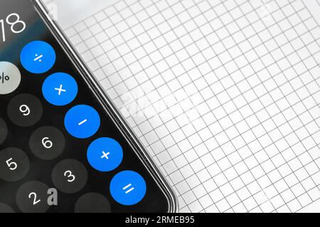 Calculatrice couchée sur la feuille vierge de papier de maths closeup. Concept d'éducation. Feuille blanche vide sur la table de travail Banque D'Images