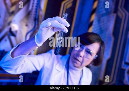 femme scientifique floue dans le gant de latex avec l'échantillon liquide dans le tube à essai dans le laboratoire d'innovation Banque D'Images