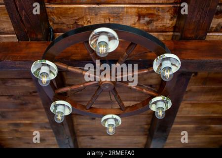 lustre fabriqué à partir d'une roue de wagon en bois, des bols rustiques et des ampoules, vue latérale douce de mise au point Banque D'Images