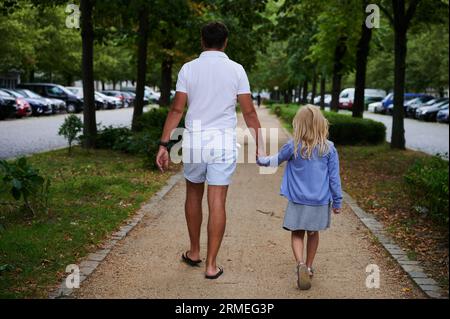 Berlin, Germany. 27th Aug, 2023. A father is walking on a sidewalk with his daughter by his hand. Credit: Annette Riedl/dpa/Alamy Live News Banque D'Images