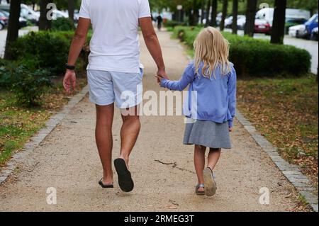 Berlin, Germany. 27th Aug, 2023. A father is walking on a sidewalk with his daughter by his hand. Credit: Annette Riedl/dpa/Alamy Live News Banque D'Images