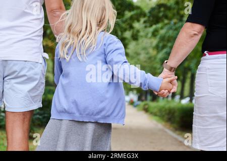 Berlin, Allemagne. 27 août 2023. Un père et une mère tiennent les mains de leur fille alors qu'ils marchent sur un trottoir. Crédit : Annette Riedl/dpa/Alamy Live News Banque D'Images