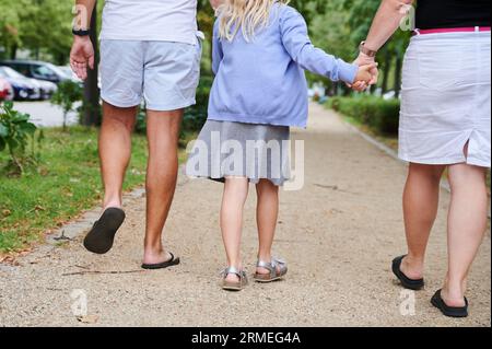 Berlin, Allemagne. 27 août 2023. Un père et une mère tiennent les mains de leur fille alors qu'ils marchent sur un trottoir. Crédit : Annette Riedl/dpa/Alamy Live News Banque D'Images