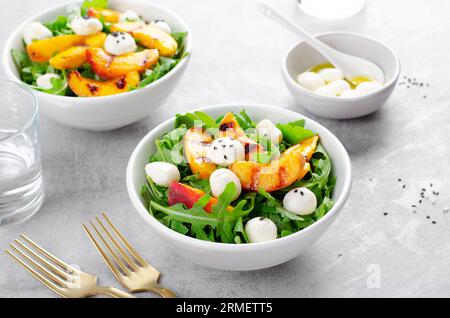 Salade de pêche grillée avec des perles de fromage roquette et mozzarella sur fond lumineux Banque D'Images