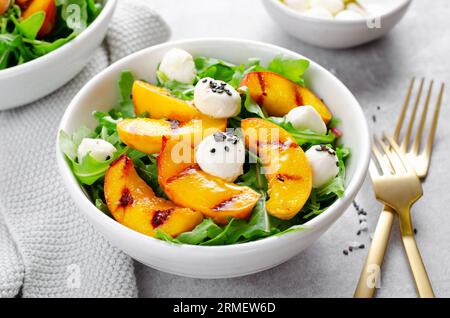 Salade de pêche grillée avec des perles de fromage roquette et mozzarella sur fond lumineux Banque D'Images