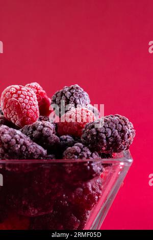 Micro gros plan de framboises dans un bol en verre avec espace de copie sur fond rouge Banque D'Images