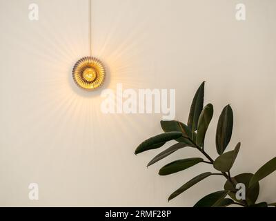 Gros plan lumière de cristal de forme ronde accrochée sur le mur blanc dans la pièce intérieure près des feuilles vertes dans le café, style minimal. Petit verre cristal vintage Mo Banque D'Images