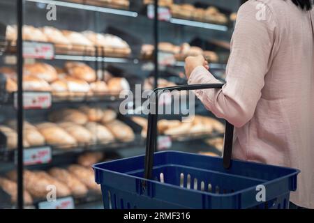Femme avec panier dans la section boulangerie du supermarché Banque D'Images