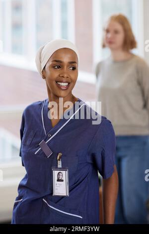 Femme médecin souriante à l'hôpital regardant loin Banque D'Images
