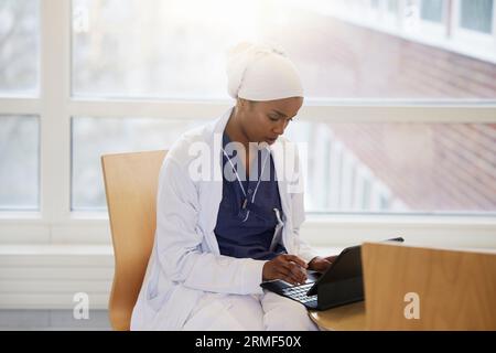Jeune femme médecin utilisant des comprimés au travail Banque D'Images