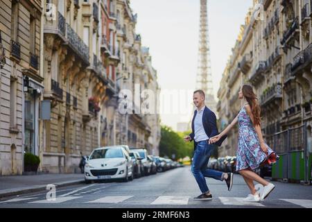 Couple romantique courant dans la rue avec la tour Eiffel en arrière-plan à Paris, France Banque D'Images