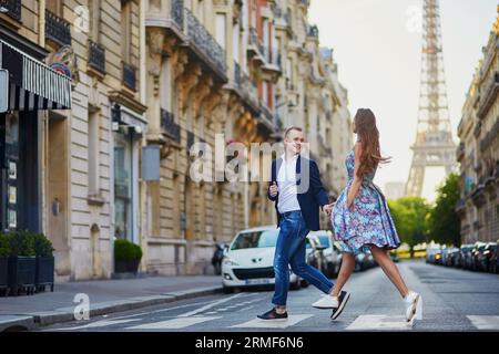 Couple romantique courant dans la rue avec la tour Eiffel en arrière-plan à Paris, France Banque D'Images