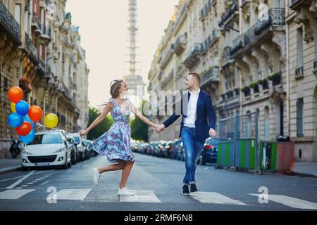 Couple romantique courant dans la rue avec la tour Eiffel en arrière-plan à Paris, France Banque D'Images